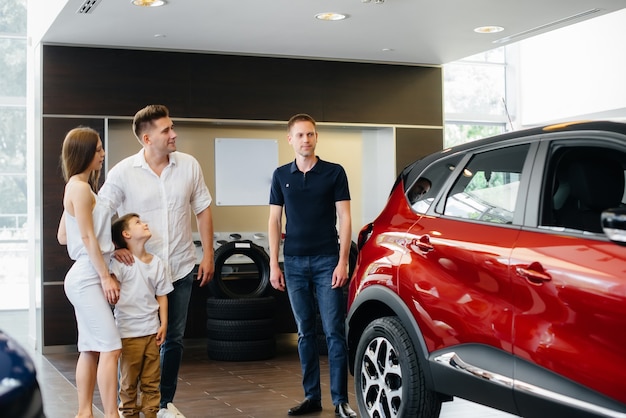 A happy young family chooses and buys a new car at a car dealership