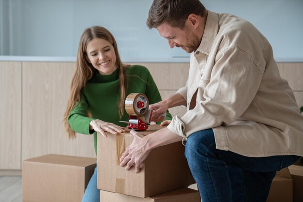 Happy young family couple man and woman packing cardboard boxes together moving in new apartment