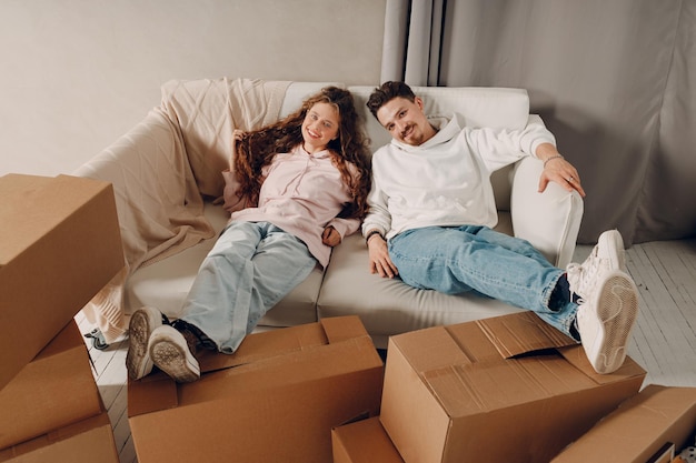 Happy young family couple man and woman relaxing after moving cardboard boxes to new estate home apartment