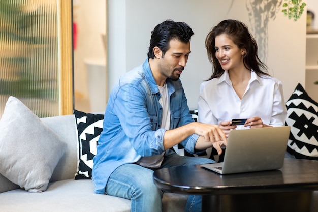 노트북 컴퓨터로 온라인 쇼핑을 하는 행복한 젊은 가족 커플. 구매 온라인 개념을 만들기.