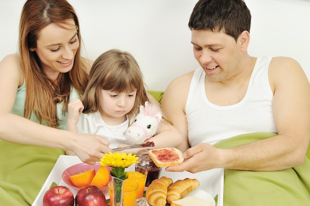 happy young family eat breakfast in bed at morning