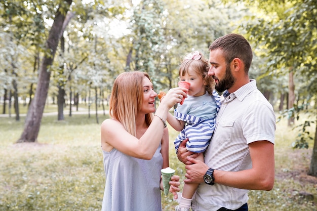 Happy young family eating ice cream and having fun outside