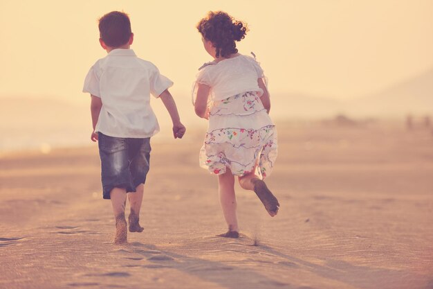 happy young family have fun on beach run and jump  at sunset