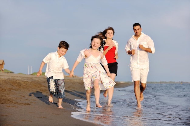幸せな若い家族はビーチで楽しく健康的なライフスタイルを送っています