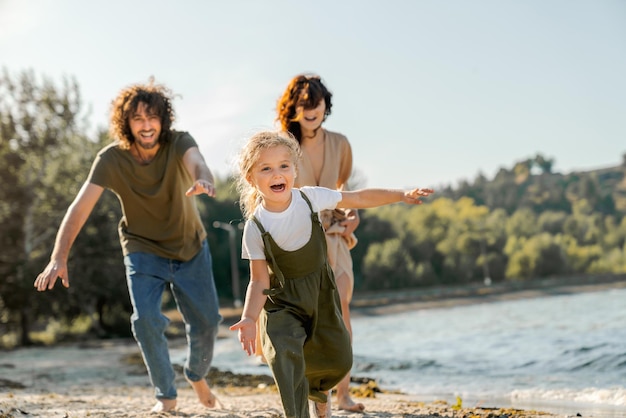 Happy young family having fun on the beach Little cute girl running along a beach