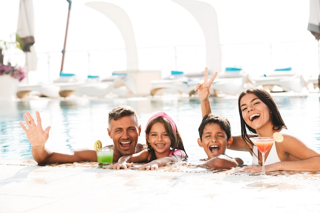 Счастливая молодая семья весело в бассейне