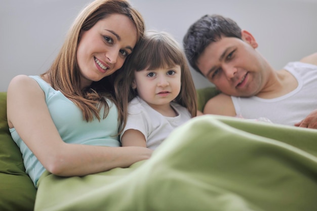 счастливая молодая семья дома отдыхает в постели