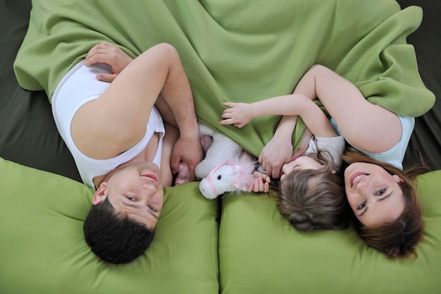 Photo happy young family at home relaxing in bed