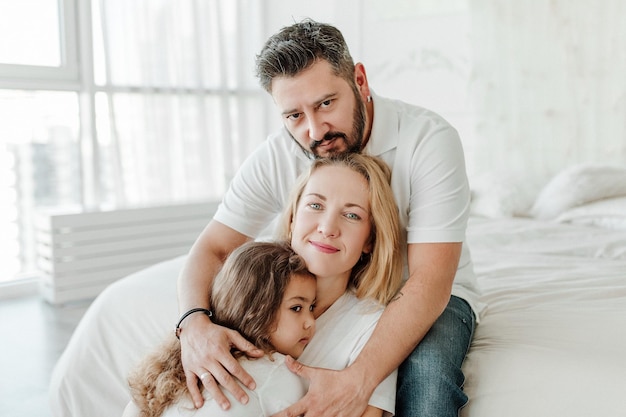 Happy young family. Man, woman and daughter. Light background, studio shot. Interracial marriage, different nationalities