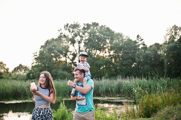 Happy young family: mother, father, children son on nature having fun.