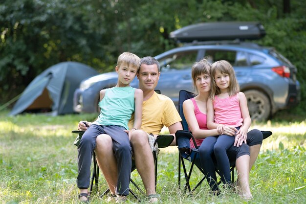 夏のキャンプ場で一緒に休む幸せな若い家族の両親と子供たち。