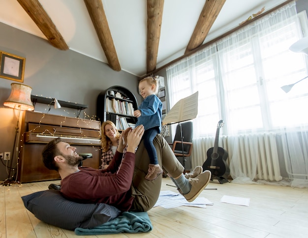 素朴な部屋で床に遊んで幸せな若い家族