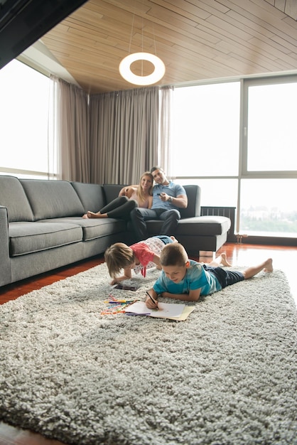 Happy Young Family Playing Together at home on the floor using a tablet and a children's drawing set