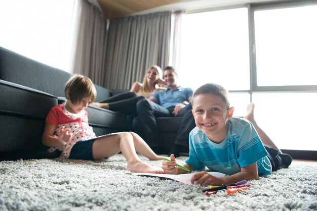 Photo happy young family playing together at home on the floor using a tablet and a children's drawing set