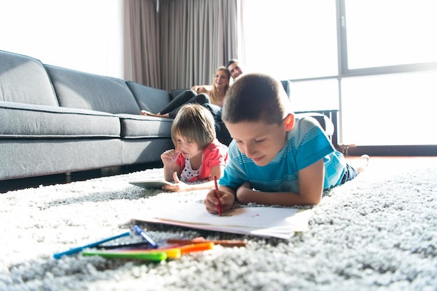 Happy Young Family Playing Together at home on the floor using a tablet and a children's drawing set