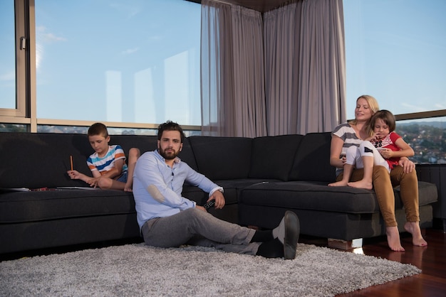 タブレットと子供の絵のセットを使用して自宅のソファで一緒に遊ぶ幸せな若い家族