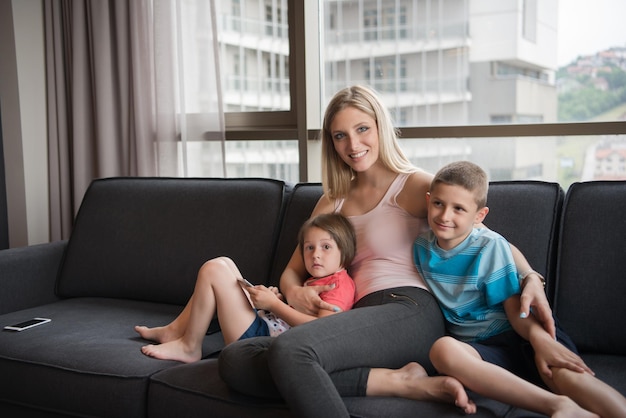 Happy Young Family Playing Together with tablet at home sitting on the sofa