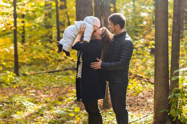 黄金色とカラフルな秋の自然の中で一緒にリラックスして幸せで若い家族。