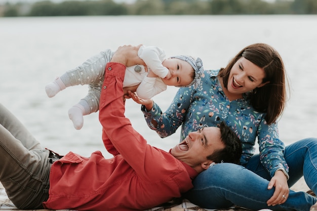 Happy young family sitting near the water.