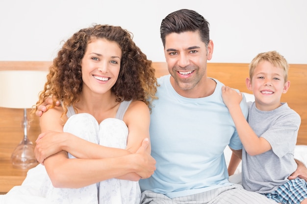 Happy young family smiling at camera on bed