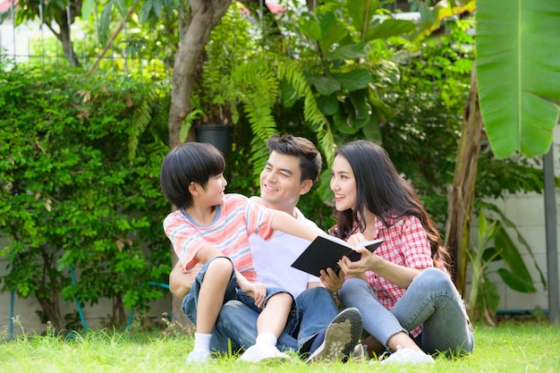 Счастливая молодая семья проводит время, играя вместе в саду перед домом на каникулах.