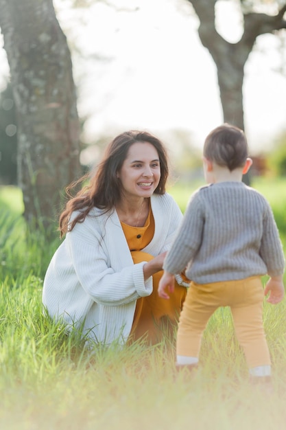 Happy young family spends time in spring blooming park Mom and little son are playing Outside