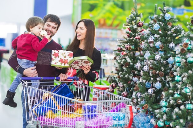 Happy young family in the supermarket chooses gifts for the new year.