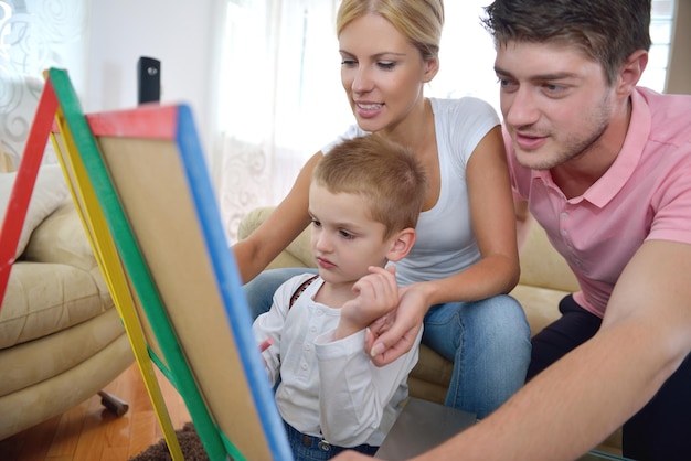 happy young family teach leassons and prepare their son for school while draw on board at home