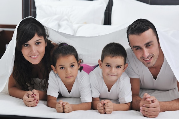 Photo happy young family in their bedroom have fun and play in bed