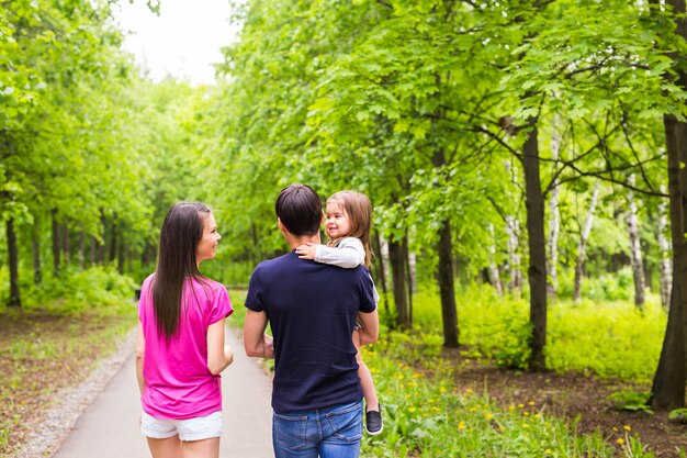 Giovane famiglia felice che cammina per strada fuori nel verde della natura.