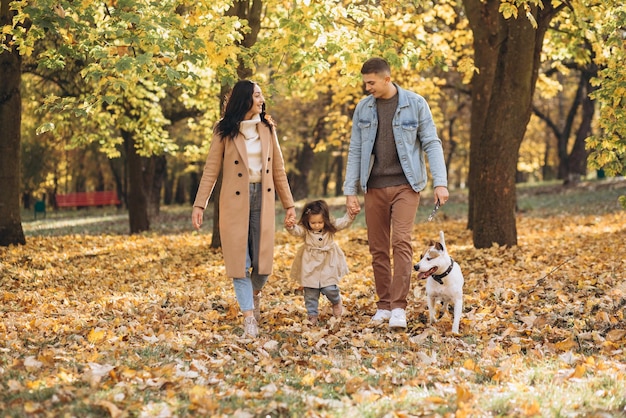 Happy young family walks and plays with a dog in the autumn park