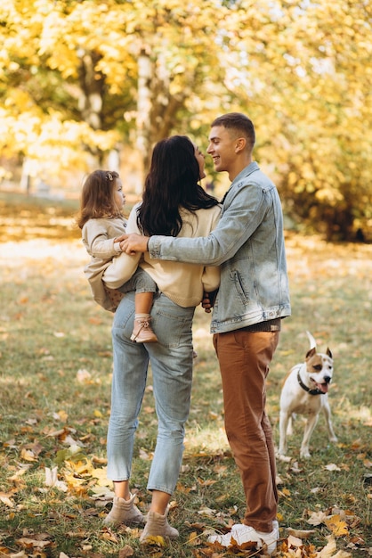 Happy young family walks and plays with a dog in the autumn park