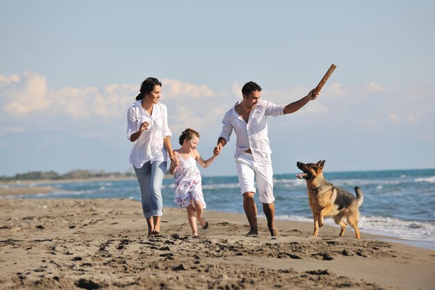 happy young family in white clothing have fun and play with beautiful dog at vacations on beautiful beach