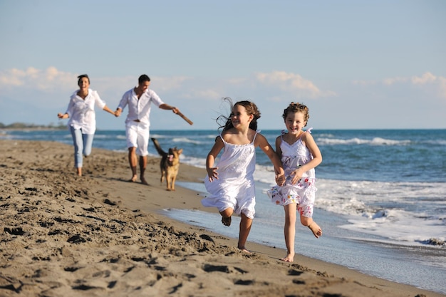 happy young family in white clothing have fun and play with beautiful dog at vacations on beautiful beach