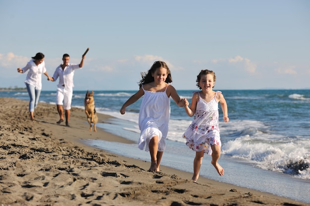 happy young family in white clothing have fun and play with beautiful dog at vacations on beautiful beach