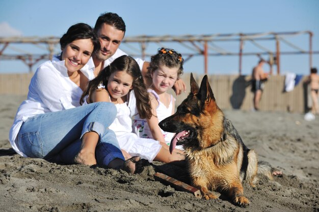 happy young family in white clothing have fun and play with beautiful dog at vacations on beautiful beach