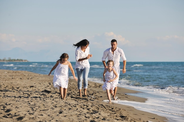 La giovane famiglia felice in abiti bianchi si diverte in vacanza sulla bellissima spiaggia