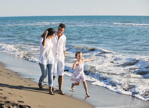 Foto la giovane famiglia felice in abiti bianchi si diverte in vacanza sulla bellissima spiaggia