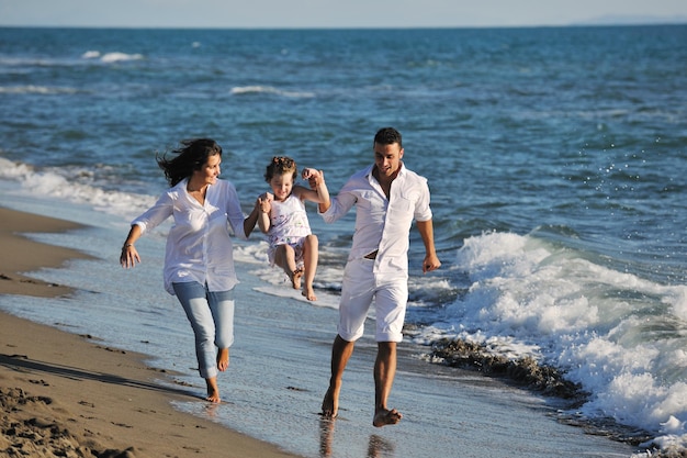 白い服を着た幸せな若い家族は美しいビーチでの休暇で楽しんでいます