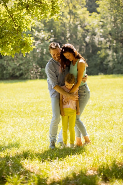 Happy young family with cute little daughter having fun in the park on a sunny day