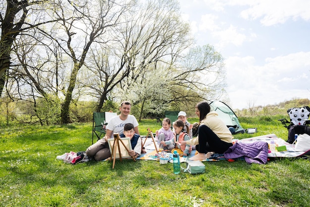Felice giovane famiglia con quattro bambini che si divertono e si divertono all'aperto durante il picnic
