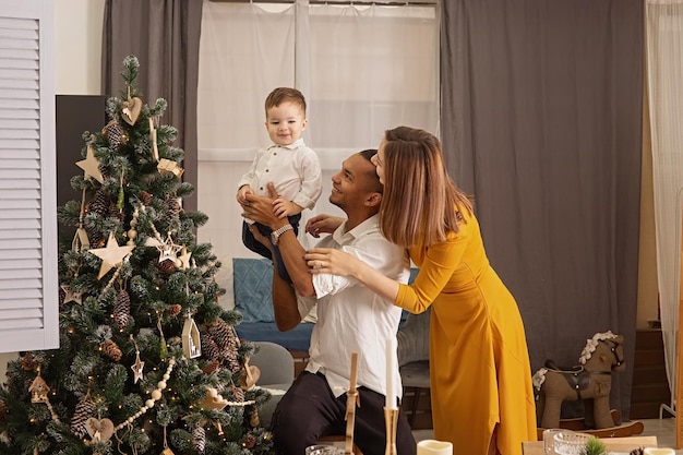 Счастливая молодая семья с маленьким сыном на рождественской елке