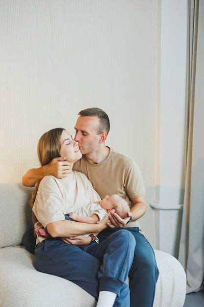 Happy young family with a newborn baby Beautiful mother and father kissing their child Parents and smiling child in arms isolated over white background
