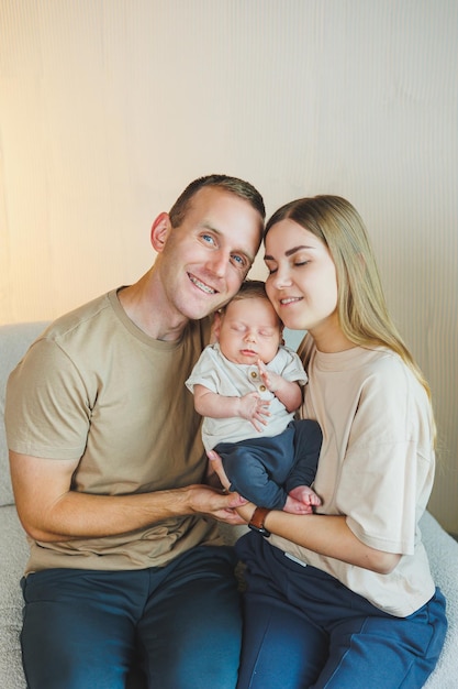 Happy young family with a newborn baby Beautiful mother and father kissing their child Parents and smiling child in arms isolated over white background