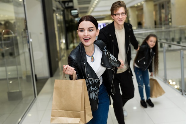 Happy young family with paper bags shopping at the Mall. Shop Windows with clothes