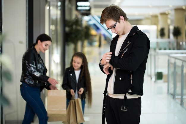 Счастливая молодая семья с бумажными пакетами, делающими покупки в торговом центре. Витрины с одеждой