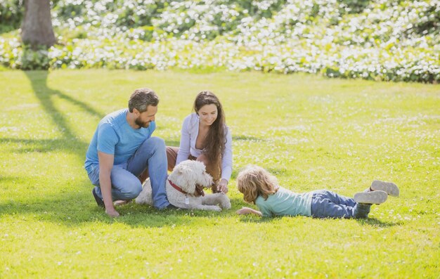 Happy young family with pet dog spending time together outside in green nature