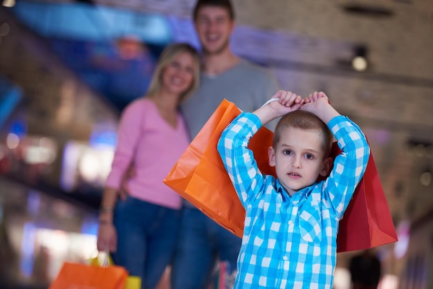 счастливая молодая семья с сумками для покупок в торговом центре