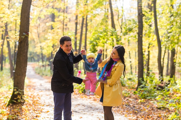 happy young family with their daughter spending time outdoor in the autumn park