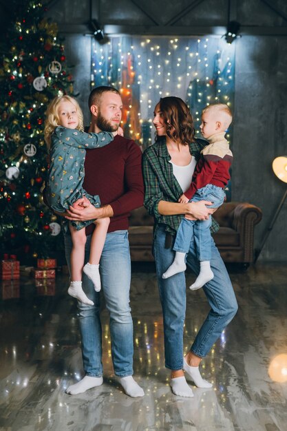 Happy young family with two children at the Christmas tree